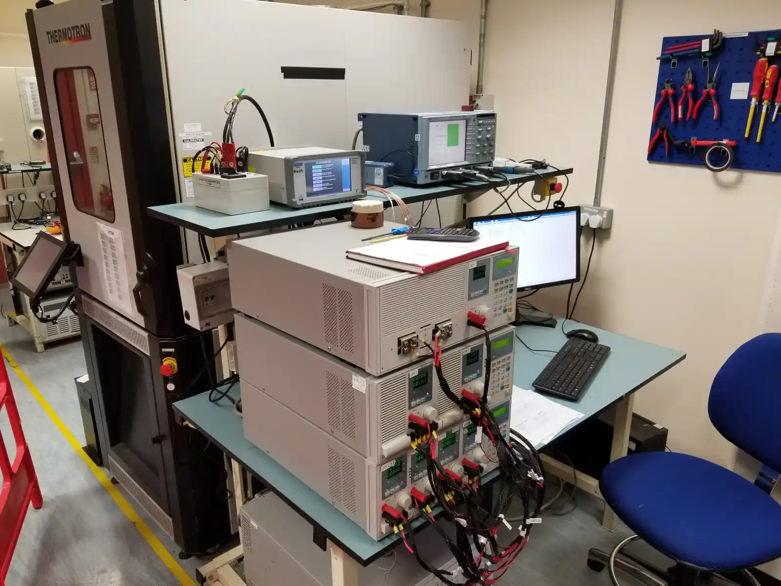 DVT test bench with Chroma AC source, electronic loads, oscilloscope, power analyser, and the ATE software running on dual monitors