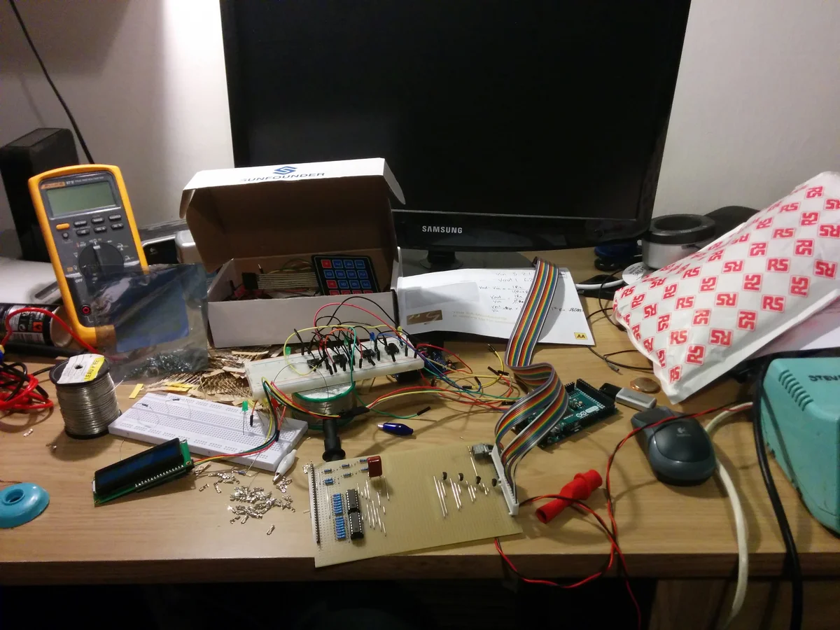 Electronics workbench with breadboard, stripboard, LCD display, and components during development